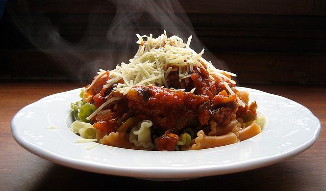 Un plato de macarrones con tomate echando humo